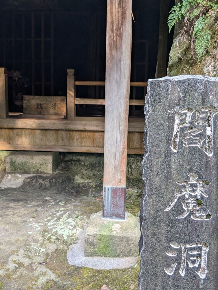 A sign showcasing a pillar with 閻魔洞, and the previous photo in the backfield