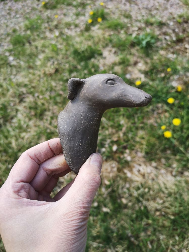 Koiran pää muotoiltu savesta, kuvattuna sivusta.