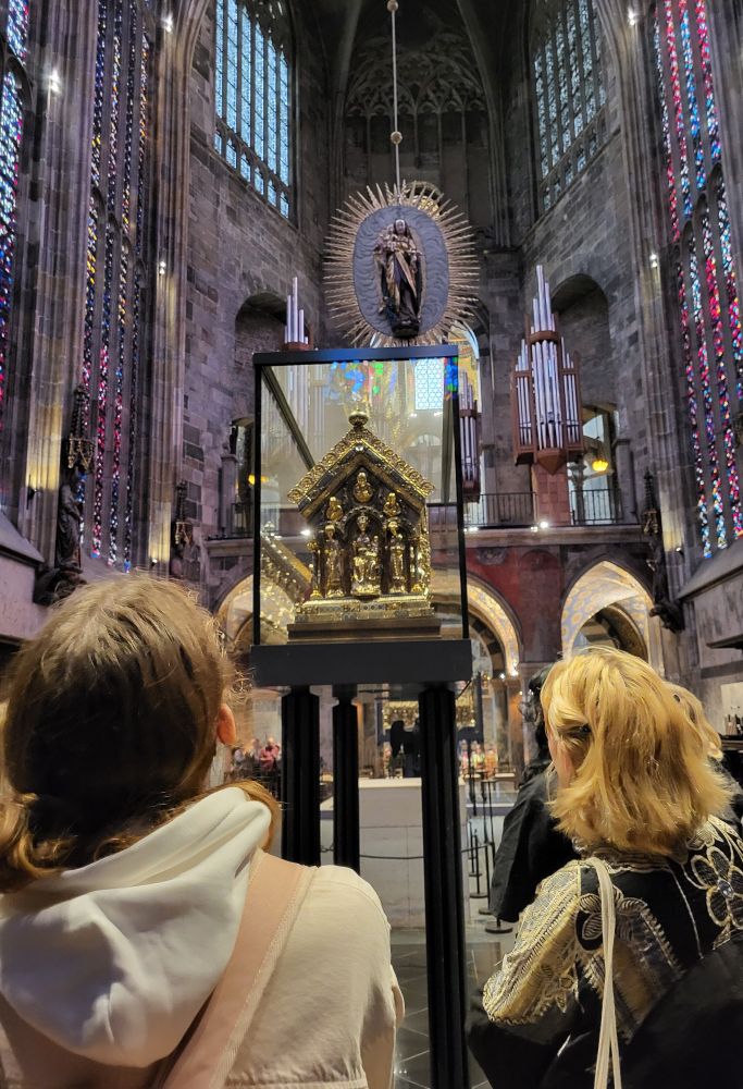 Blick auf den Karslschrein, davor Studierende, dahinter der Chor des Aachener Doms nach Westen