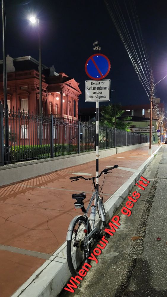 A photo of a bicycle parked outside of the Parliament of Trinidad and Tobago. 
