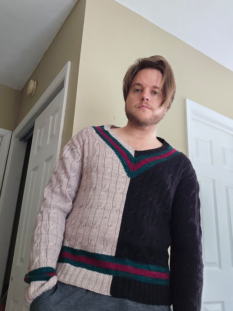 A man wears a cabled tennis sweater. This sample is from an early prototype in 2021 and the pattern dimensions and construction have changed.