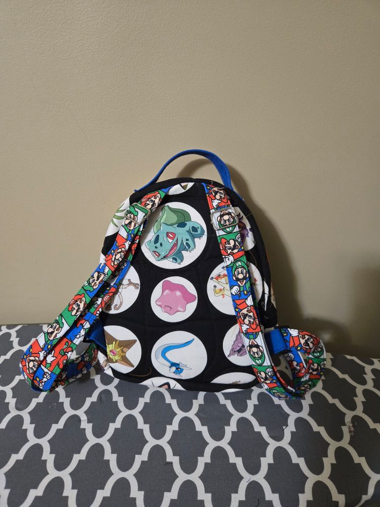 The back of the backpack with pokemon fabric and straps with mario and Luigi on them
