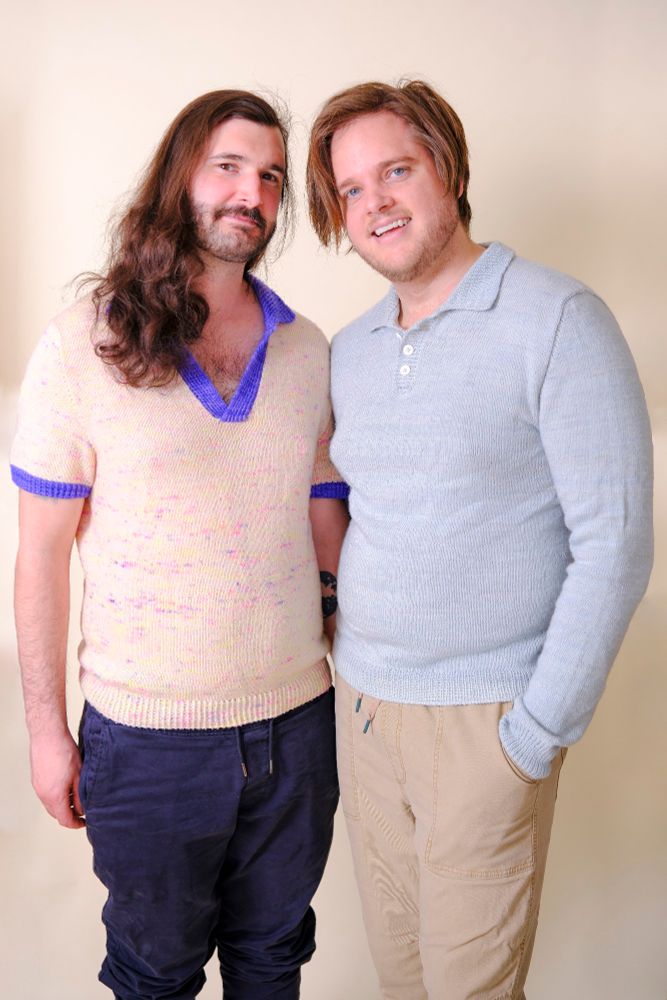 Two men embrace. One of the left is wearing a speckled short sleeve polo with an open button placket. This pattern is called The Modern Knit Polo. The one of the right is wearing a blue long-sleeved polo with a buttoned up closed placket. This pattern is called The Classic Knit Polo.