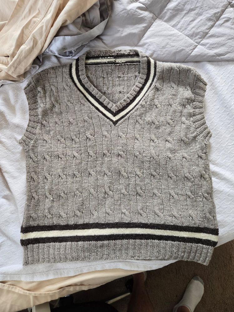 A sweater vest laying on an (unmade) bed (oops lol)
