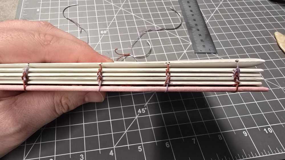 Detail shot showing the two-tone braid formed from stitching lavender and rust thread into the book spine