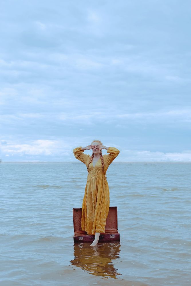 Girl standing in a suitcase like on a boat and float on the sea