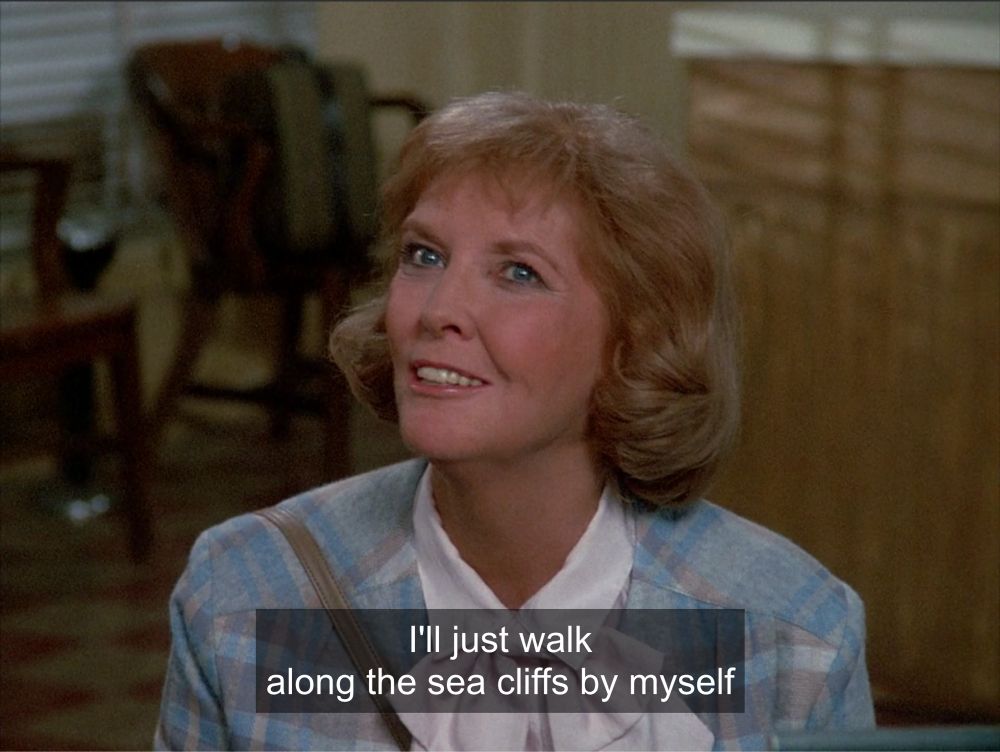 Same scene continues. She now looks somewhat wistful. Closed caption reads “I’ll just walk along the sea cliffs by myself”