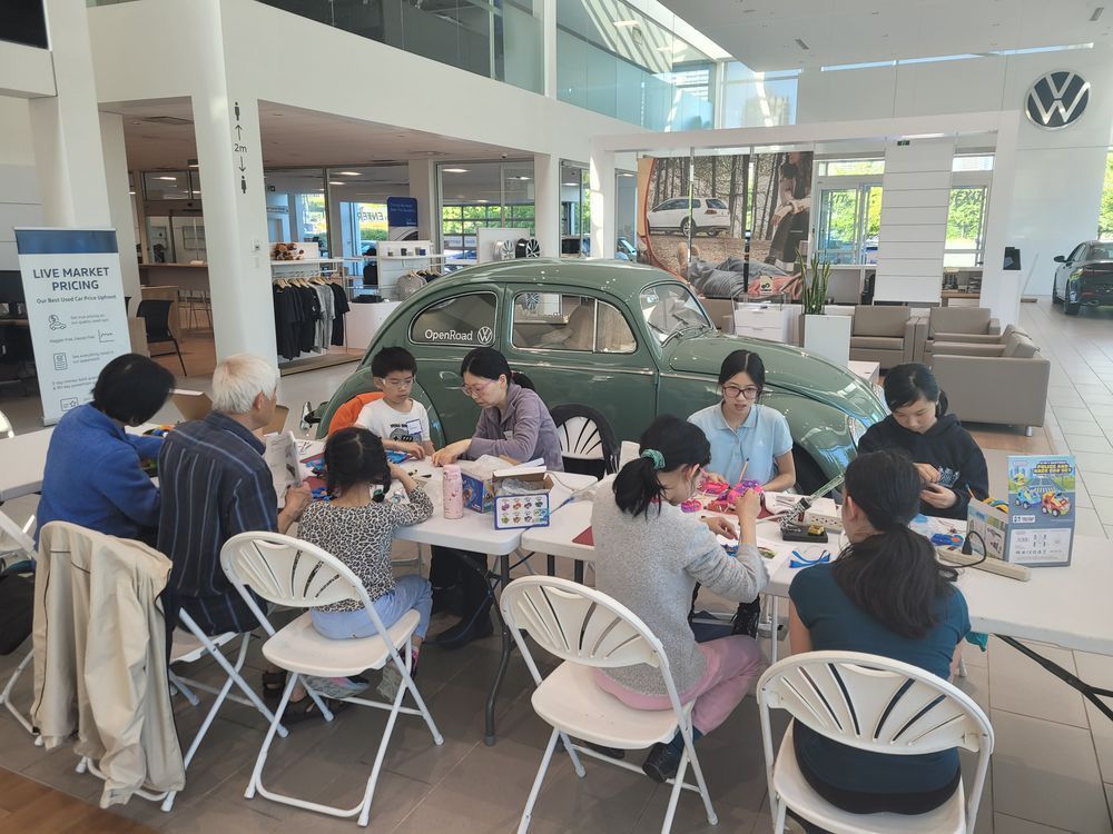 Youth volunteers and families at OpenRoad Volkswagen Burnaby work on adapting toys.