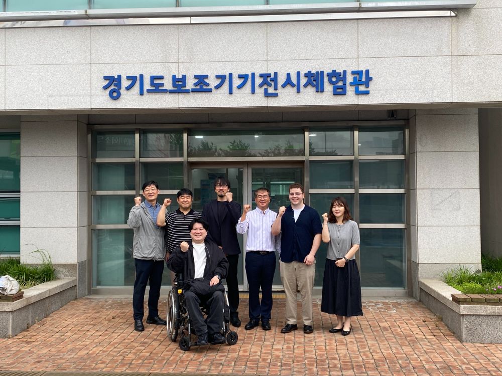 Tyler with representatives from the Gyeonggi Rehabilitation Engineering Service Research Support Center in front of the centre.