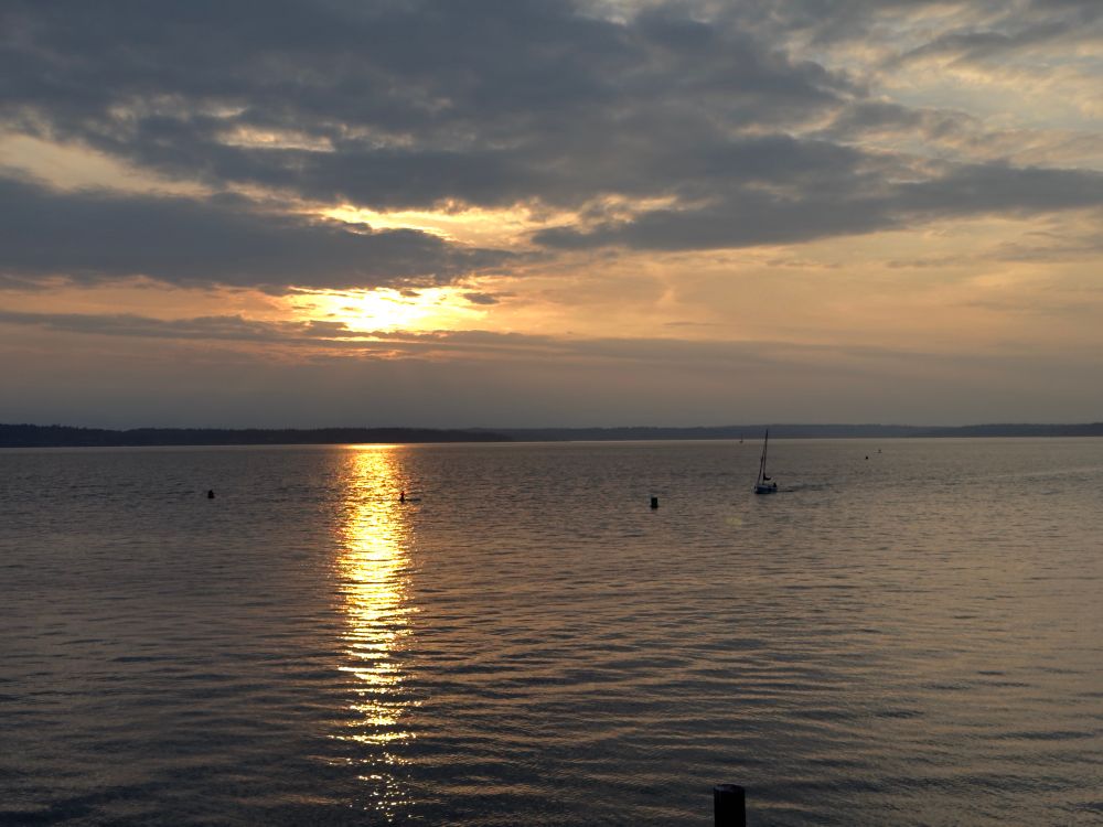 The sun “sets” into the clouds over Puget Sound, the long trail of the sun’s rays bouncing off the water
