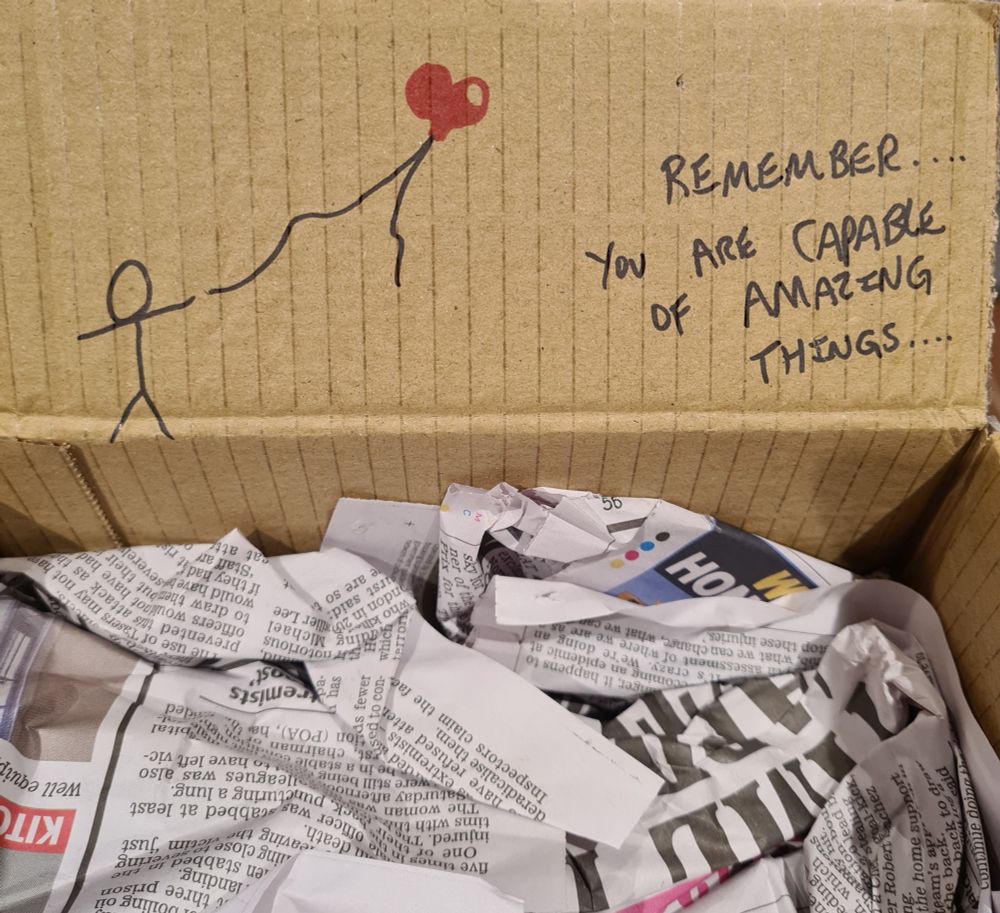 An open package, with a handwritten message from the company that says "Remember, you are capable of amazing things ..." next to a stick figure holding a red heart-shaped balloon.