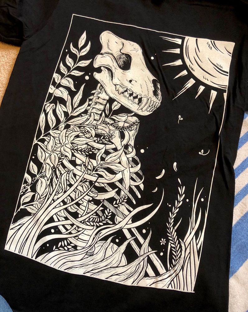 A black t shirt with white screenprint featuring a human skeleton with a canine skull head