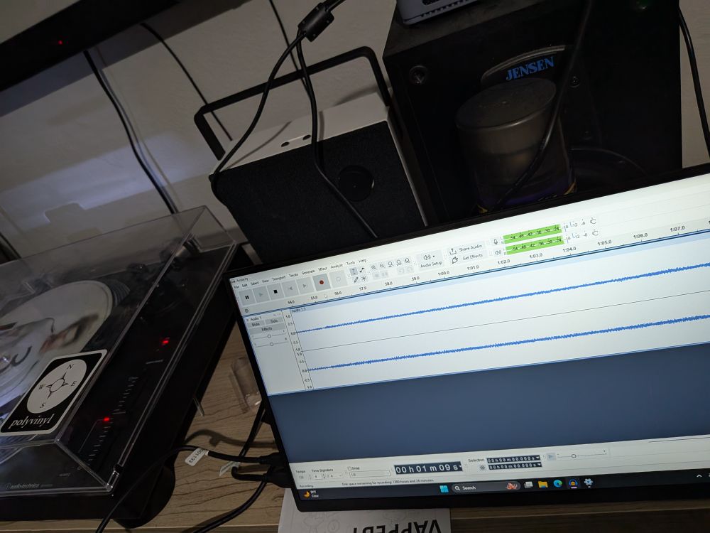 Photo of a computer monitor running an audio file in audacity, and to the left is a record player plugged into a mini pc