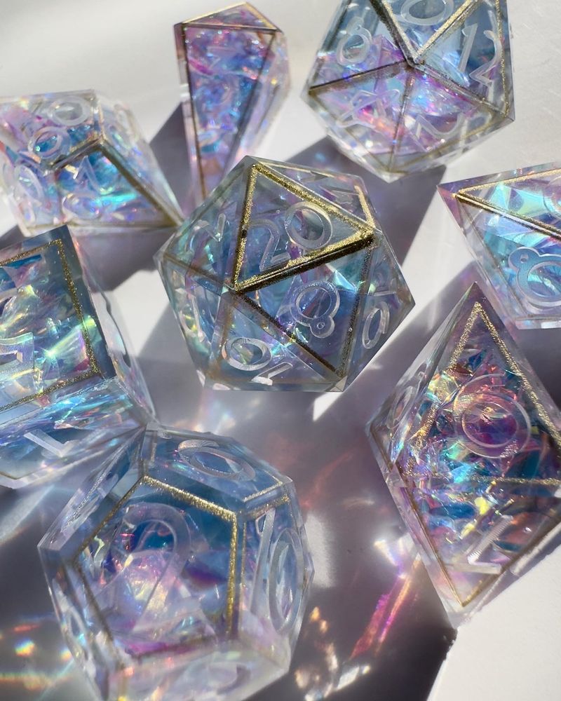 An unfinished pastel dice set with holographic mylar, lined in gold.