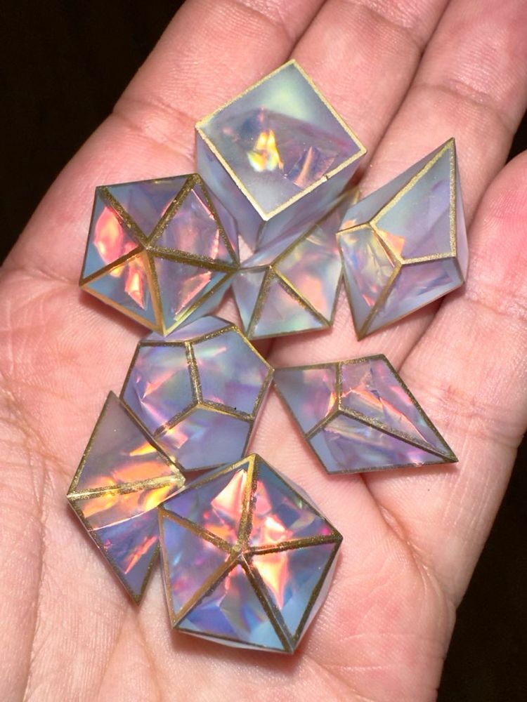 a set of pastel dice blanks with holographic mylar inside, lined in gold