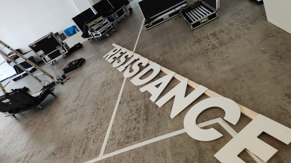 Großer Raum mit Kisten auf Rollen und der Schriftzug Resisdance liegt am Boden 
