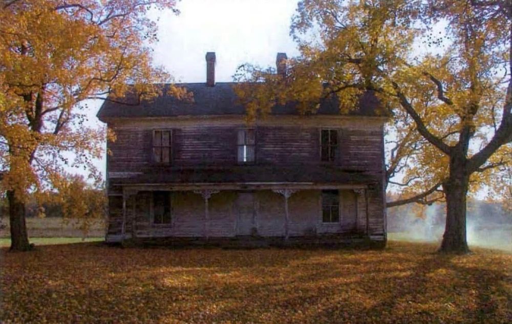 Photo of an old, two-story farmhouse with a front porch.