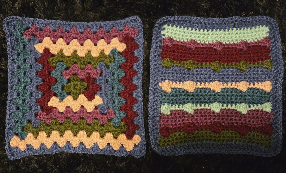 Two colorful squares made of yarn laid out on a black rug next to each other. 