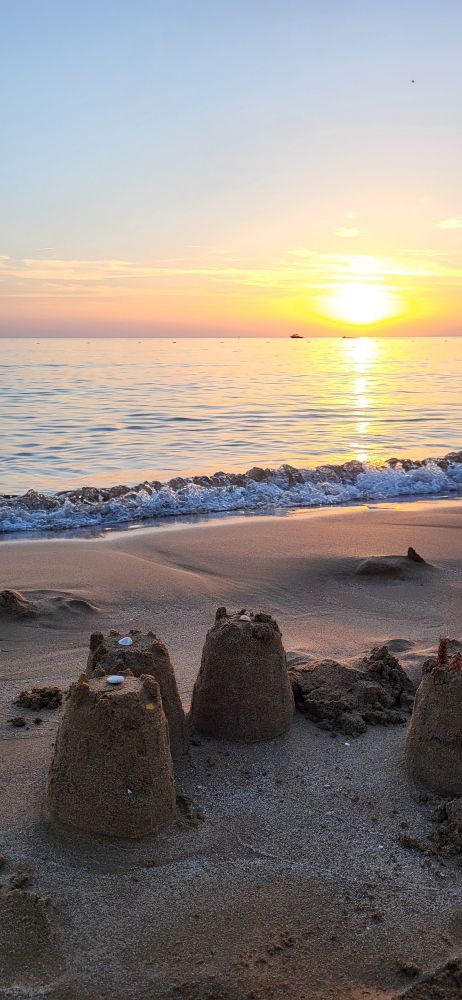 Ein Sonnenuntergang am Meer mit Sandburg im Vordergrund
