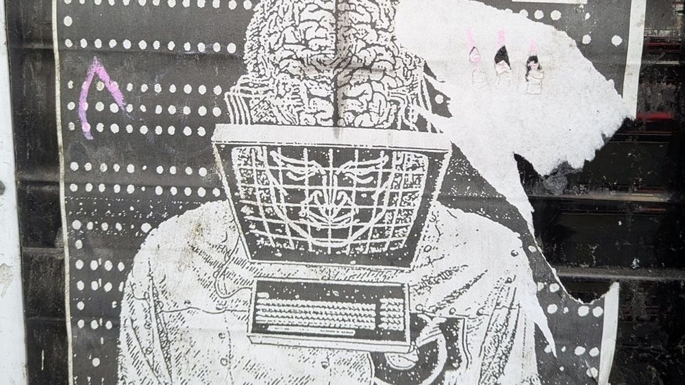 Algorithms are prisons that control you: A surreal poster illustration depicts a person with their brain exposed, attached to a cage-like computer monitor with a keyboard.