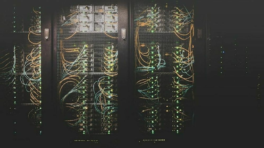 A data center server rack is filled with various cables and illuminated indicator lights.