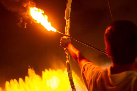 A person preparing to fire a flaming arrow