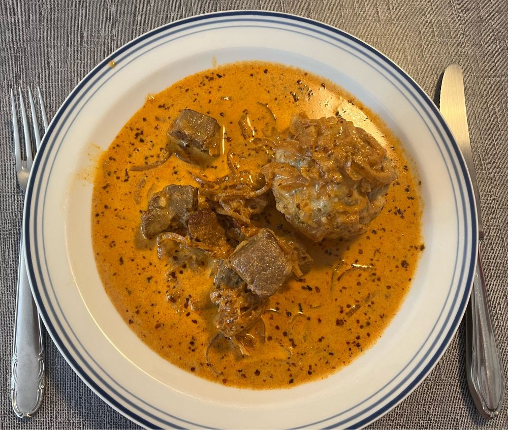 Ein Teller mit Paprika-Rahm-Gulasch und Semmelknödel