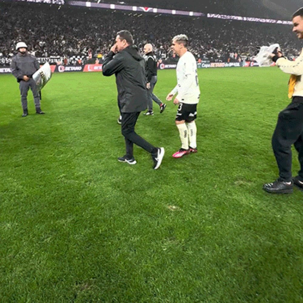 a group of men are standing on a soccer field with a man holding a pillow in his hand .