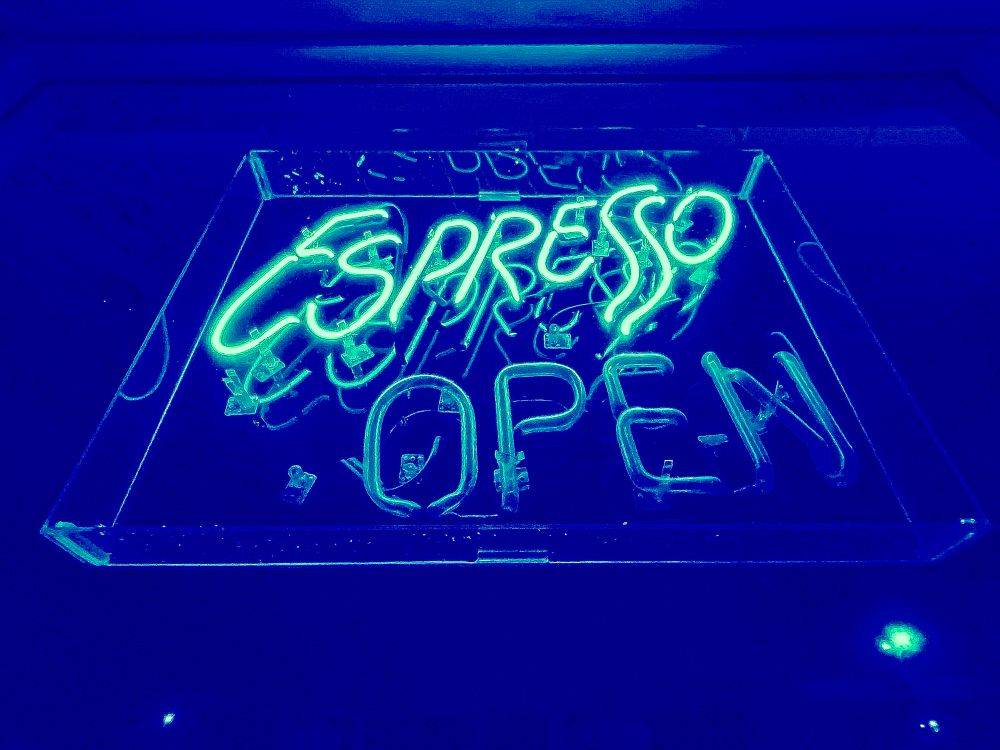 A neon sign at night advertising espresso. The darkness in midnight blue. 