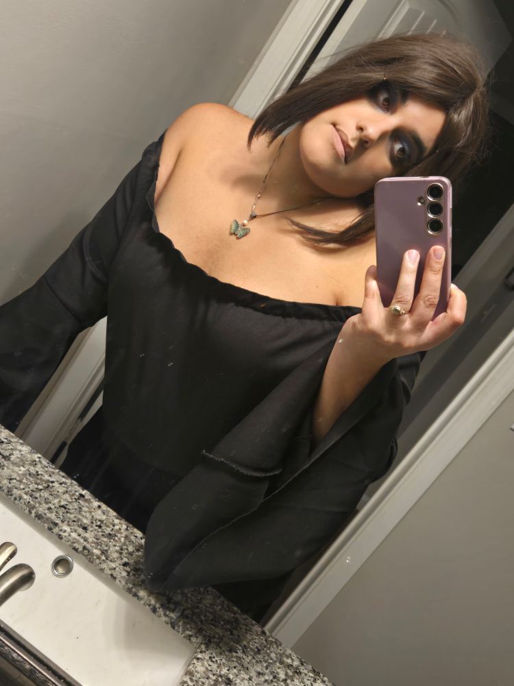 Mirror selfie of Ira, wearing a black top that hangs off her shoulders