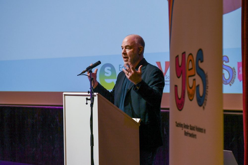 Jackson Katz of Mentors in Violence Prevention stands at a podium talking.