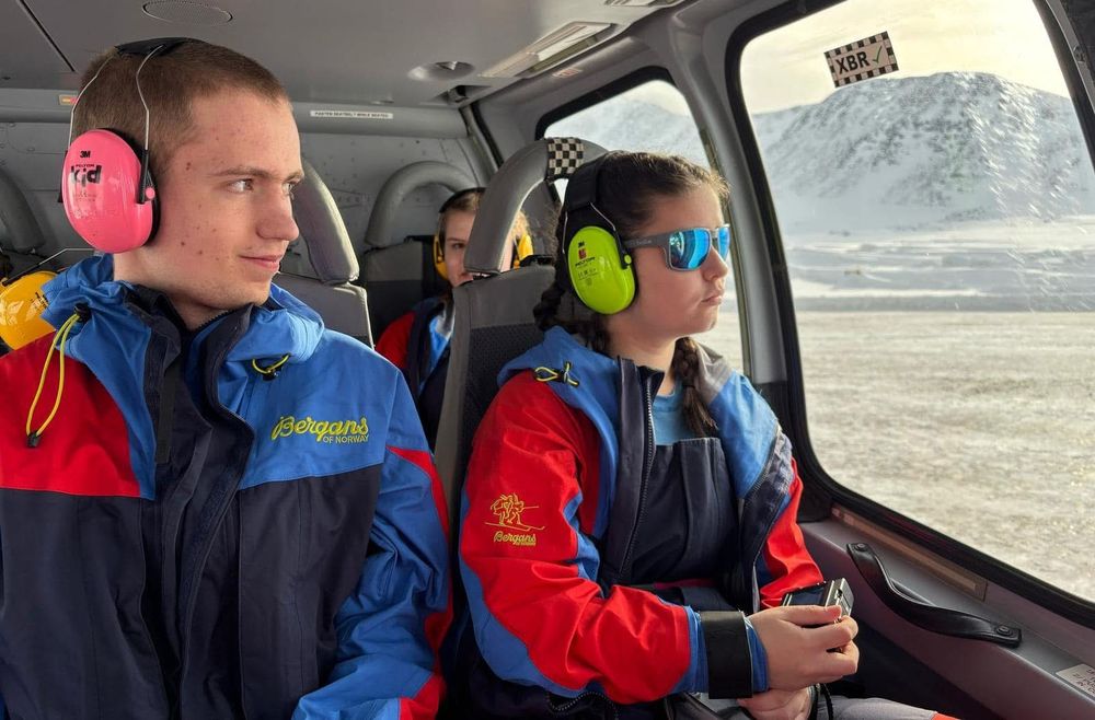 Two pupils look out the window of a helicopter.
