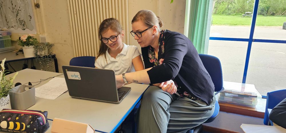 A teacher and a pupil looking at a laptop.