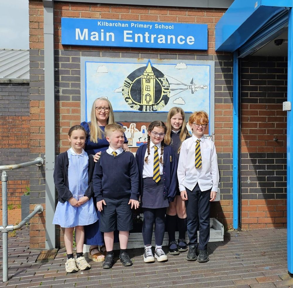 Acting head teacher Jennifer Walsh with five pupils outside the main entrance to the school.