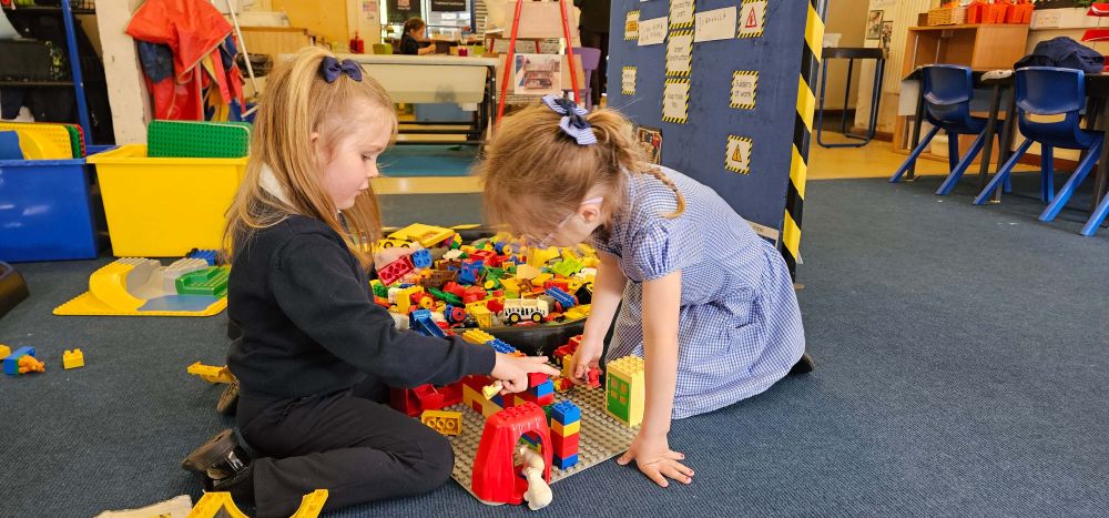 Two young pupils sitting on the floor playing with coloured blocks.