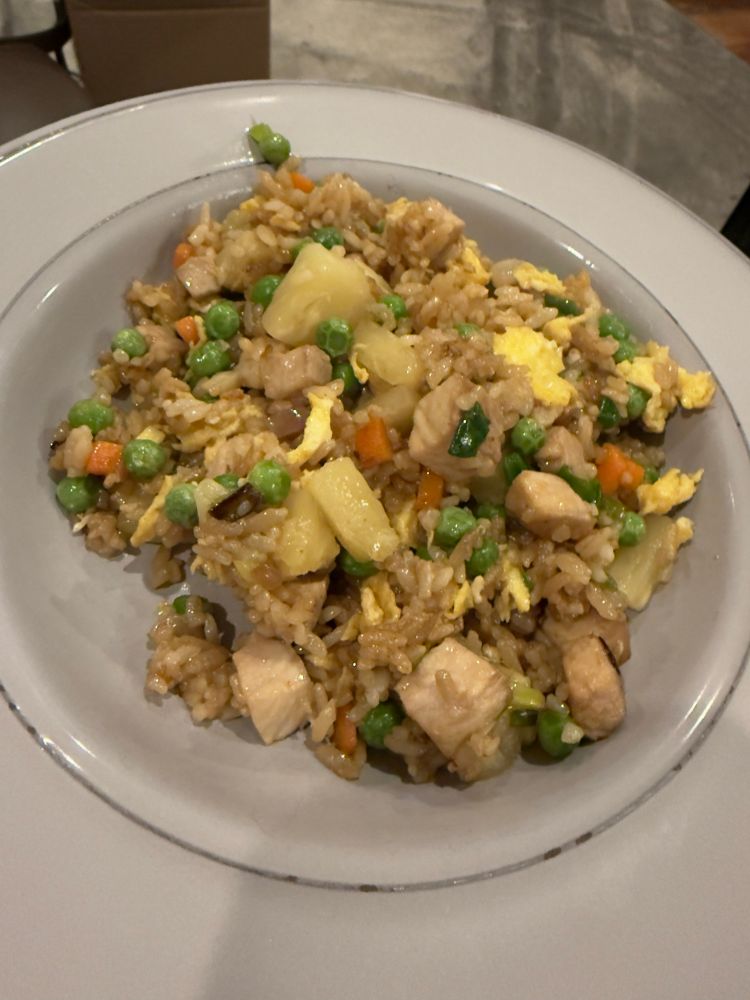 A light grey bowl filled with fried rice. You can see bits of carrot, green peas, scallions, and chunks of pork and pineapple. 