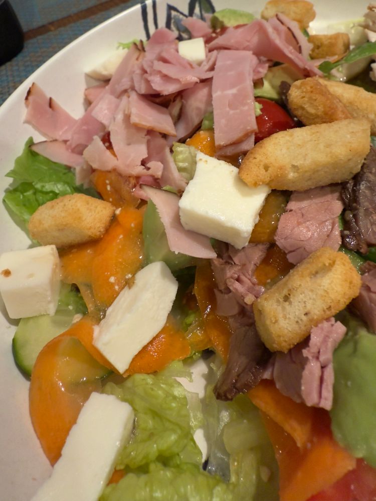 Romaine lettuce with chunks of fresh mozzarella, carrot ribbons, croutons, chopped roast beef and ham on top. 