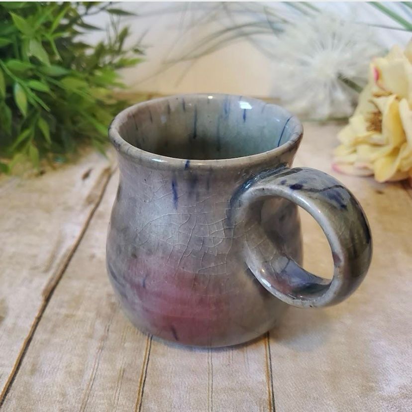 A light blue ceramic mug with dark blue and red accents plus a circular handle