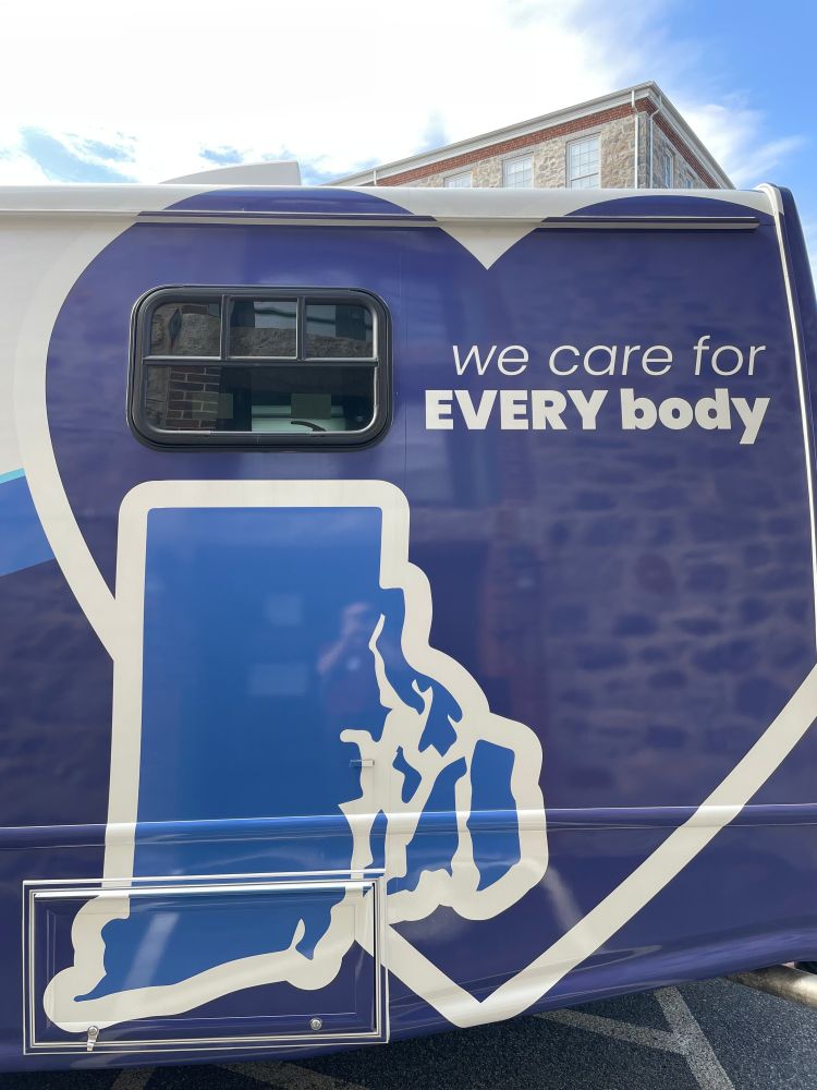We Care For EVERYBody says the copy on the unit's side inside a big blue heart with a decal of the state of RI.