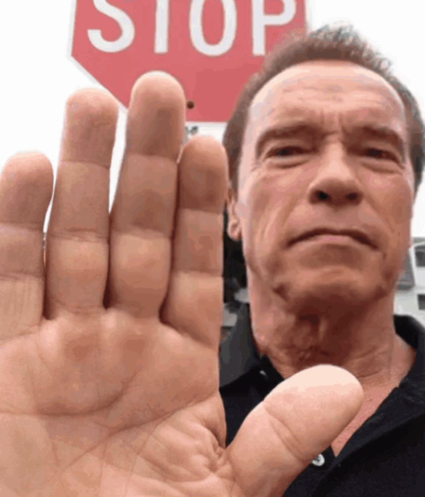 a man holds his hand up in front of a red stop sign