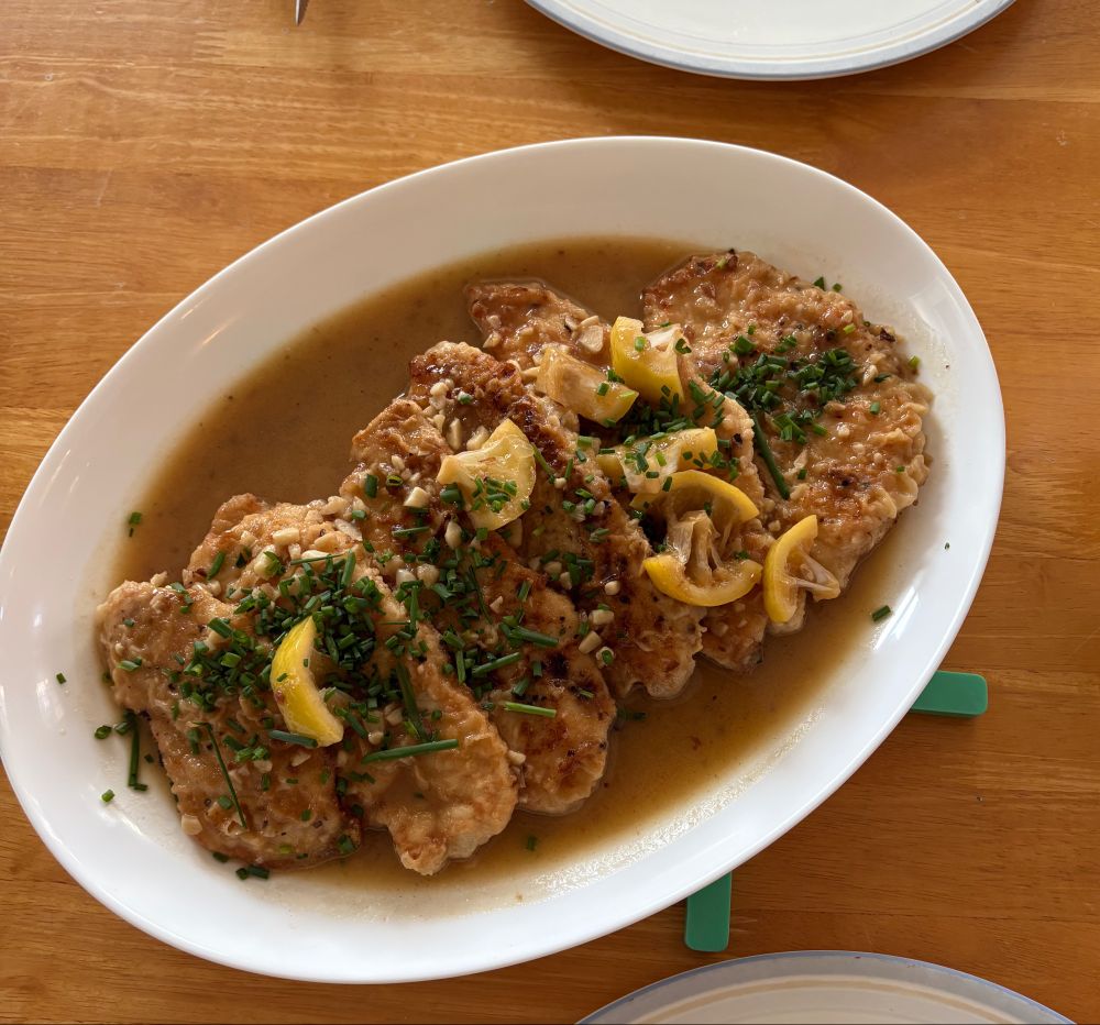 overhead shot of chicken cutlets with lemon pieces and chives 