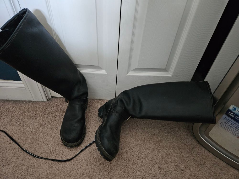 A pair of tall engineer boots in front of a closet door.