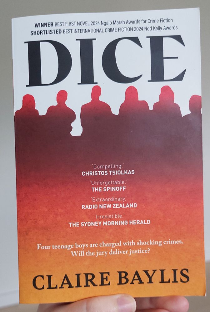 A book called Dice by Claire Baylis. The subtitle of the book says Four teenage boys are charged with shocking crimes. Will the jury deliver justice? The book cover has white at the top and silhouettes of six people in a dark red in the top middle fading to lighter orange at the bottom.