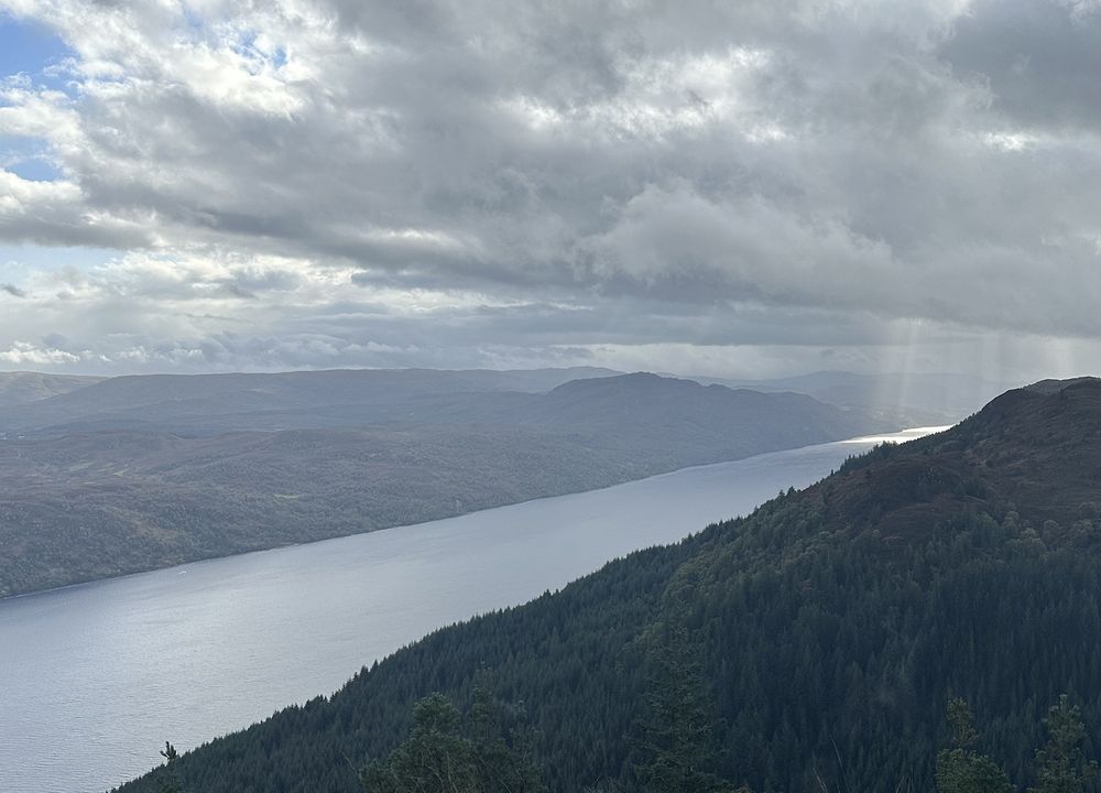 Loch Ness, photographed from high ground on the loch's north shore. Beams of sunlight appear through the clouds on to part of the loch.