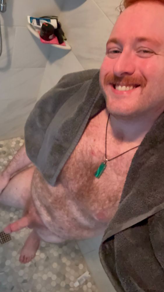 Me smiling at the camera with a grey bath towel on my shoulders green Malacate necklace on and nothing else standing in the shower drying off fat cock out air drying. 
