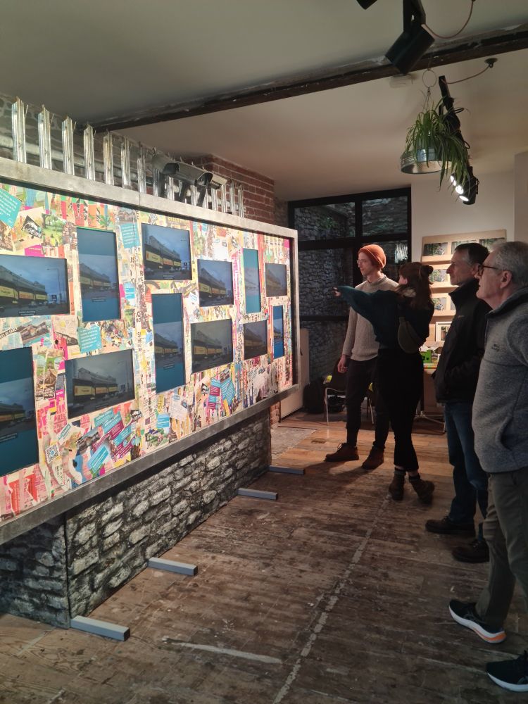 A billboard art installation in an art gallery with a crowd looking on. 
