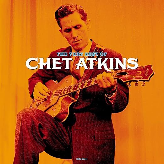 Black and white photo of Chet Atkins with his guitar against a 1960s orange background 
