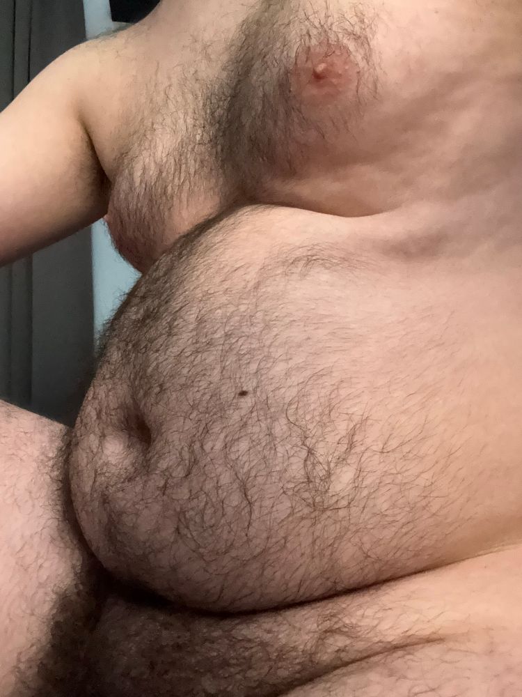 Hairy man sat nude in front of the camera. His penis just barely visible at the bottom of the frame