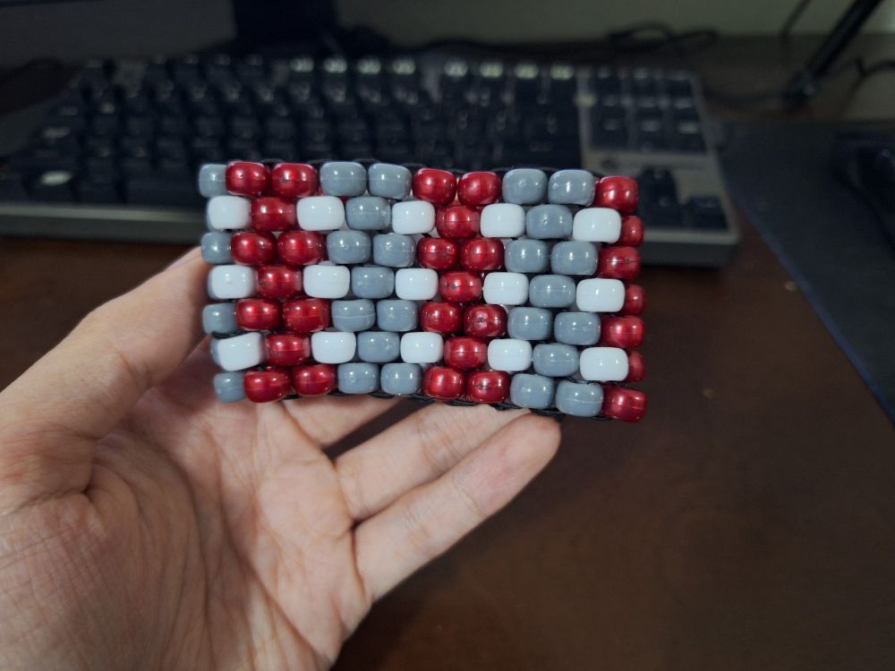 A kandi (beaded) cuff in red, gray, and white.