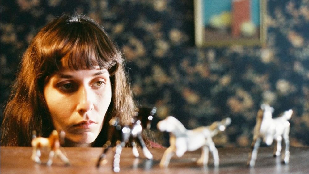 Kay in the movie Sweetie. Her face is just visible above the table covered in her small ceramic ponies.